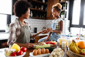 Mother and child in a kitchen smiling while sharing healthy food.